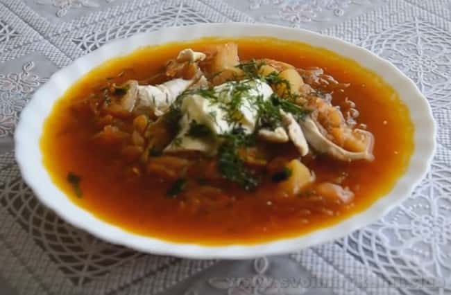 Подавайте борщ из курицы со свежей сметаной и зеленью.